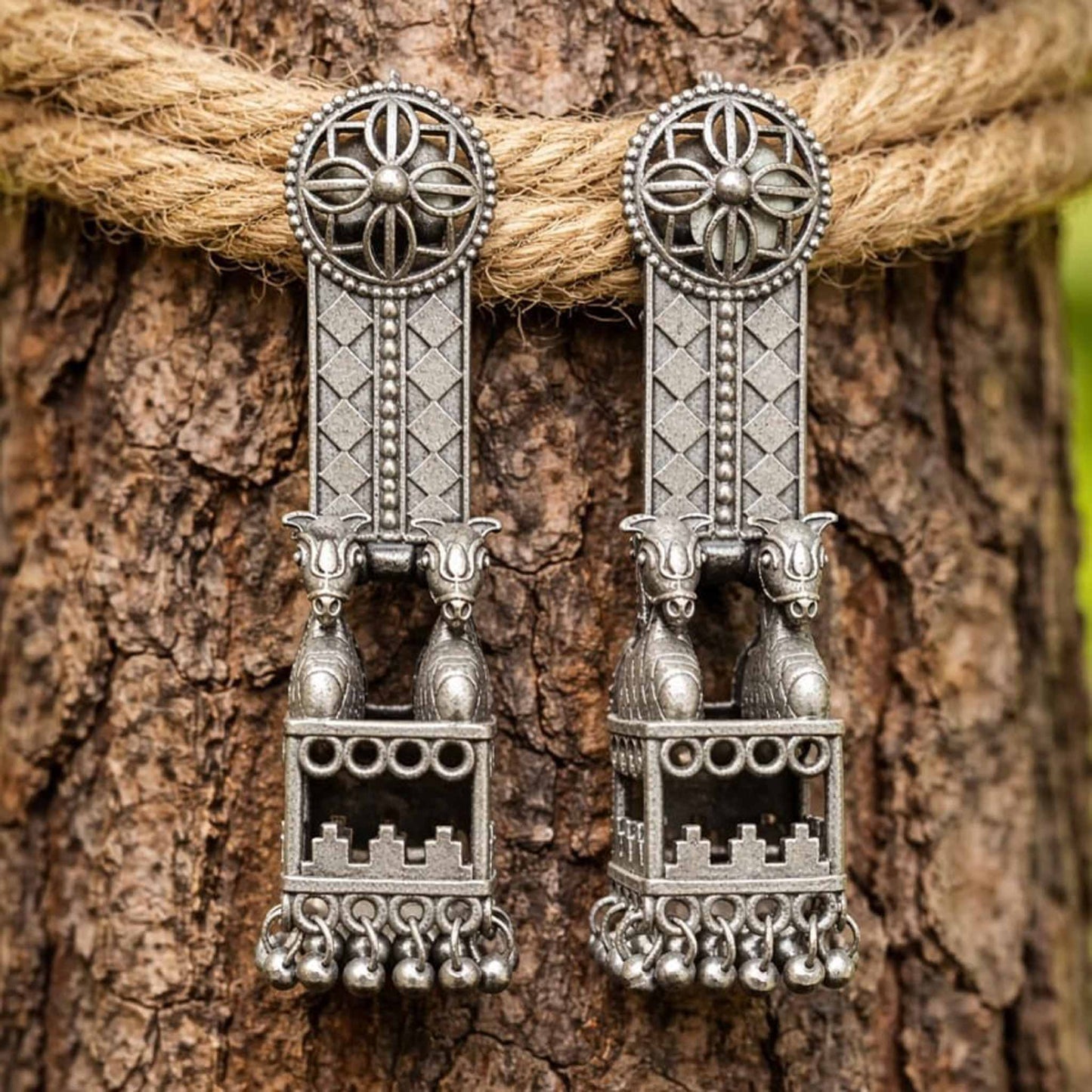 Traditional horse jharokha earrings displayed on tree bark