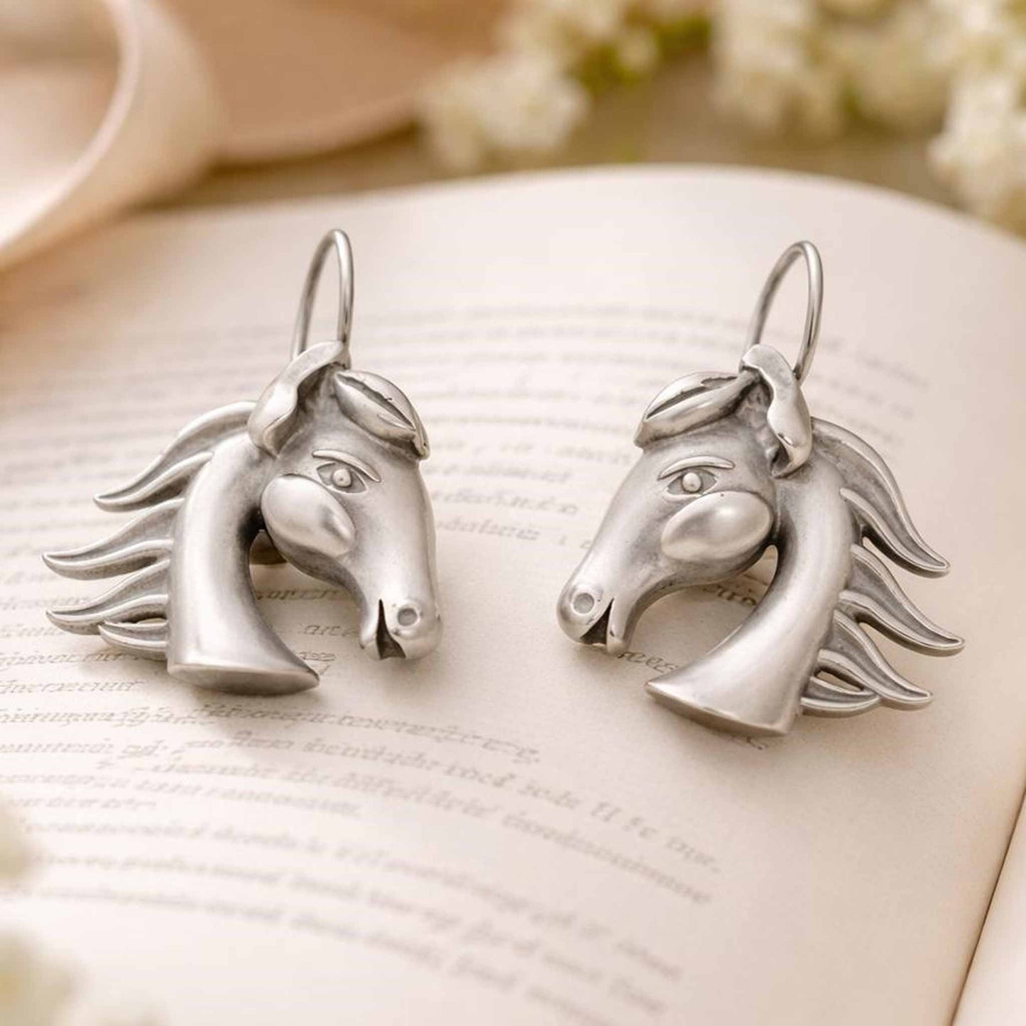 German silver horse head earrings styled on open book background
