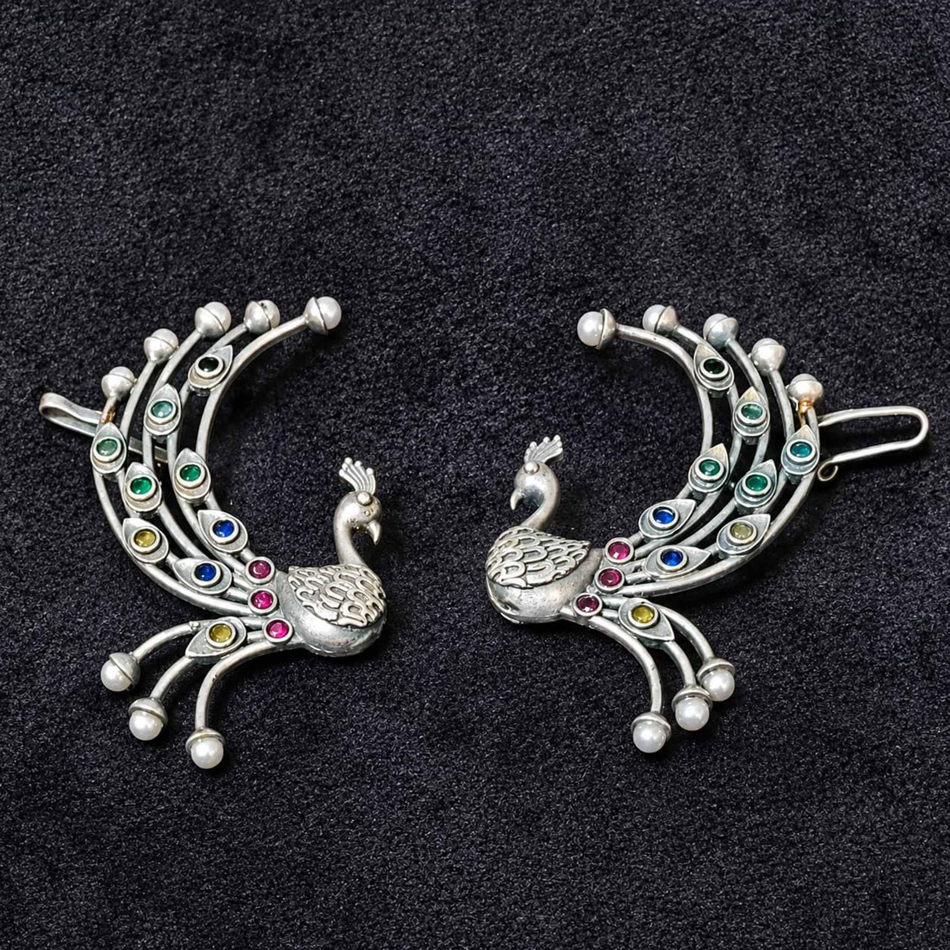 Peacock ear cuff earrings on black background