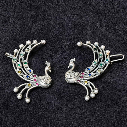 Peacock ear cuff earrings on black background