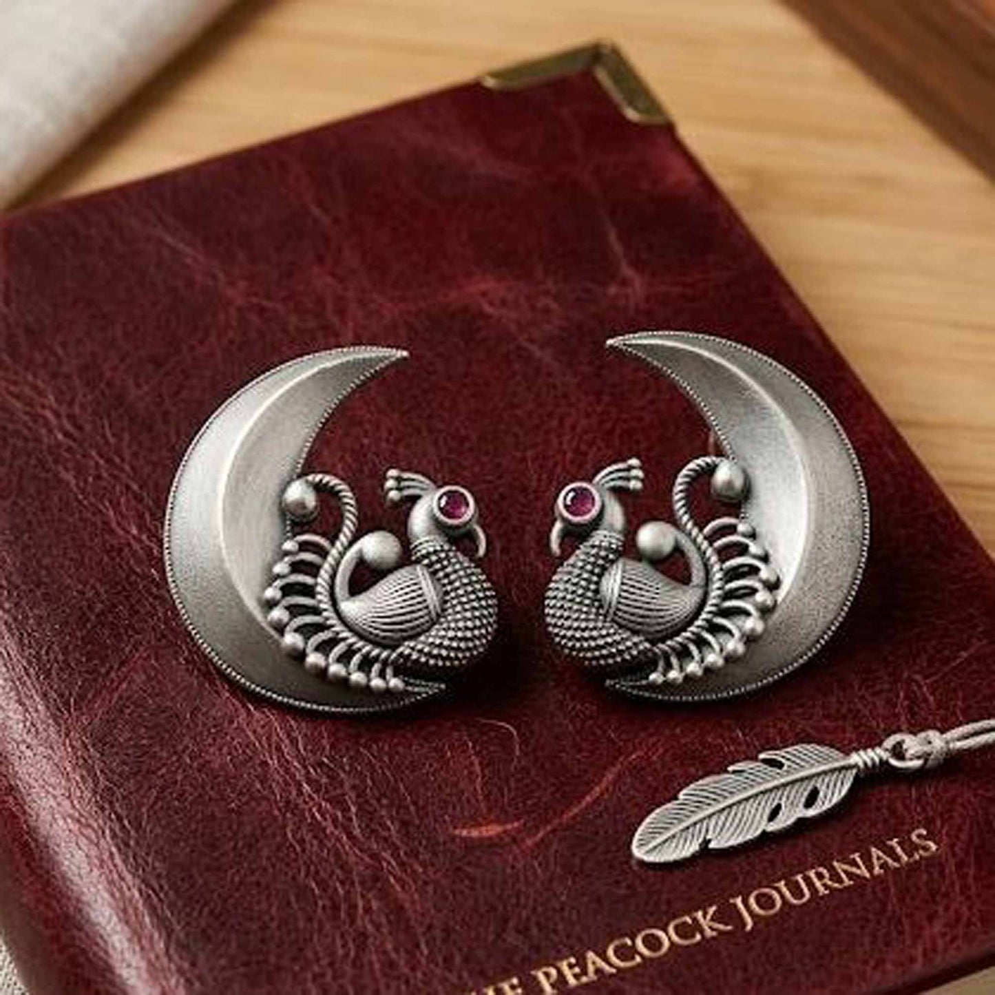 Traditional peacock moon earrings displayed on leather journal