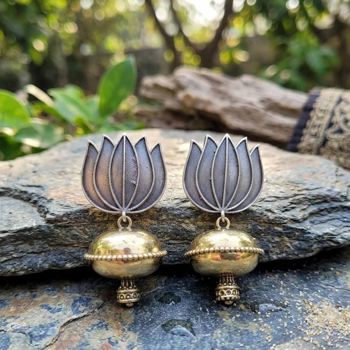 Lotus dome jhumka earrings displayed outdoors on stone