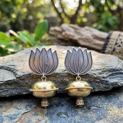 Lotus dome jhumka earrings displayed outdoors on stone