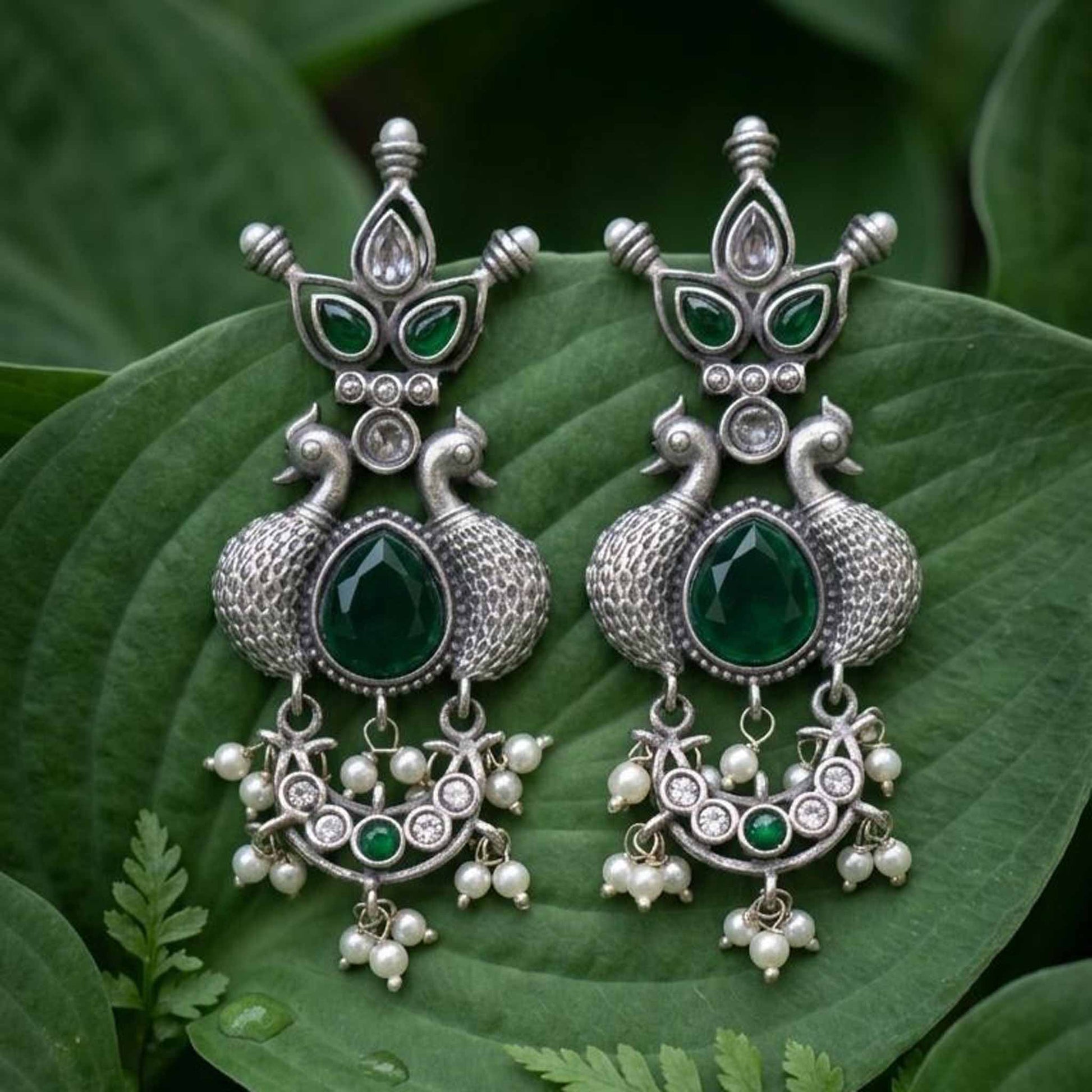 Emerald peacock pearl earrings on green leaf