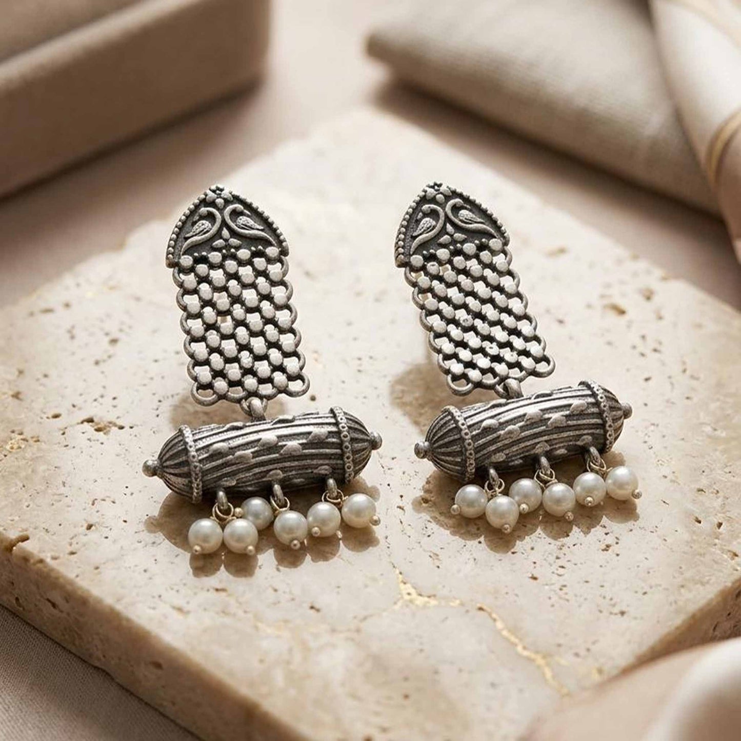 Traditional pearl dangler earrings displayed on stone surface