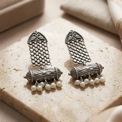 Traditional pearl dangler earrings displayed on stone surface