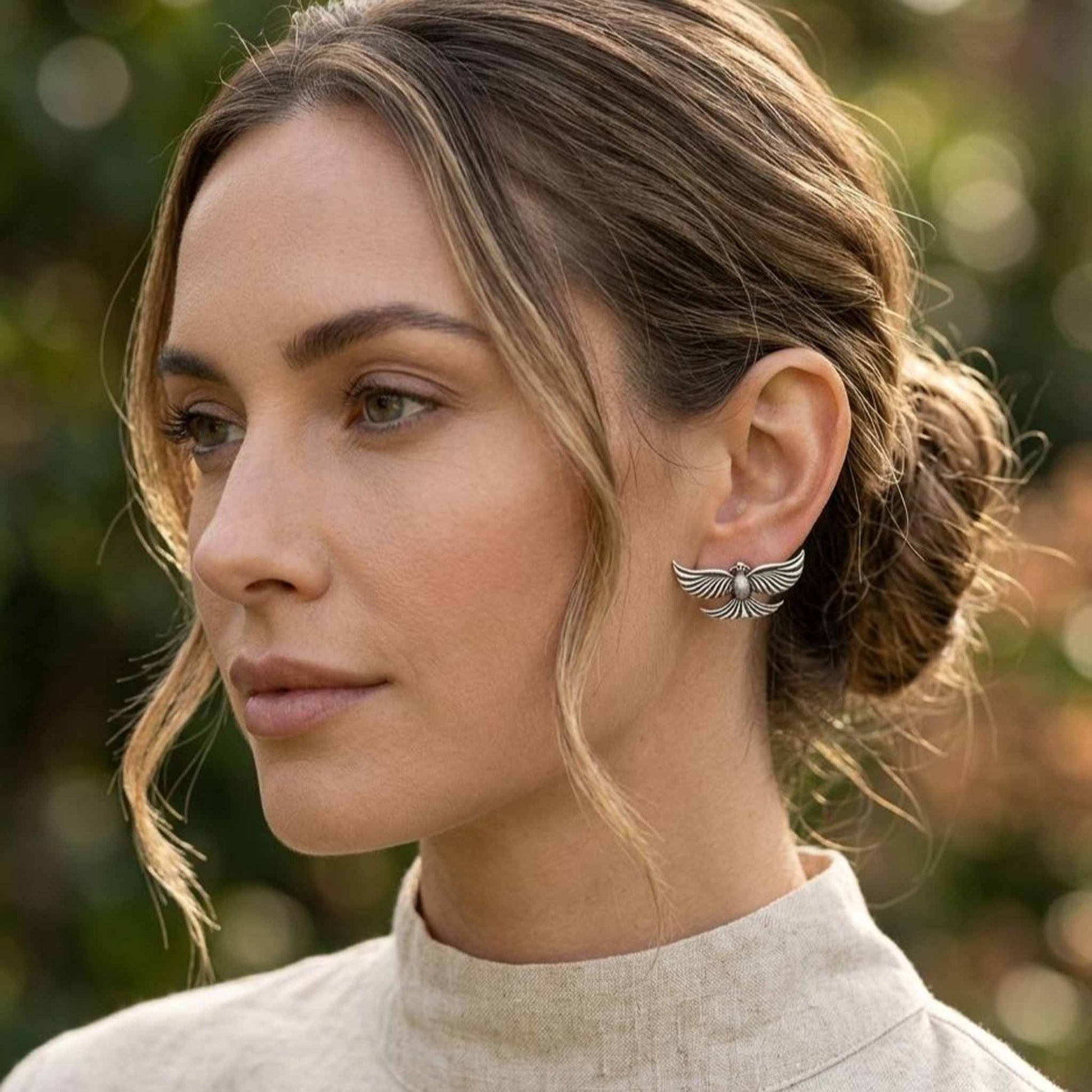 Silver flying bird earrings worn on ear styling image