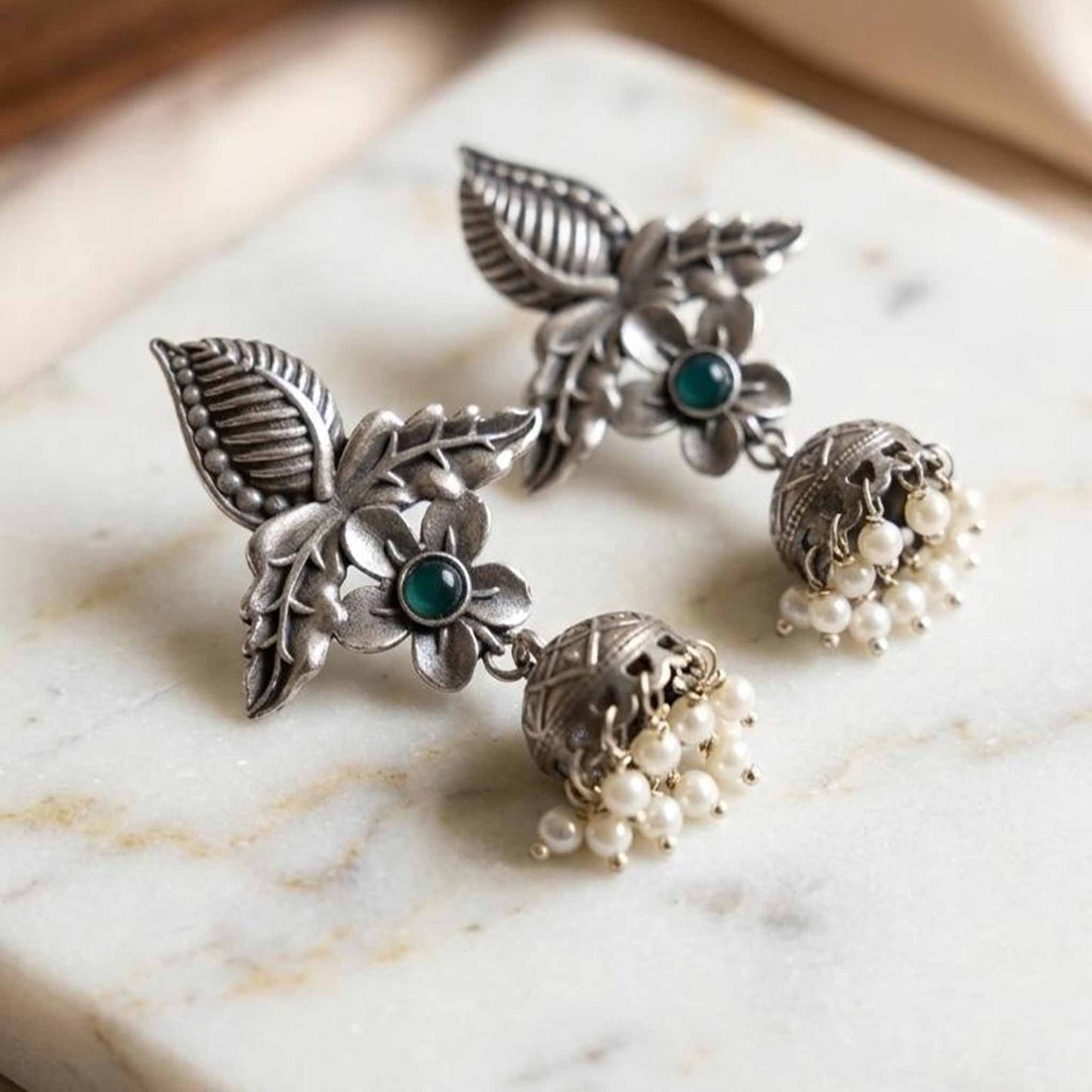 Detailed flatlay of floral pearl ghumki earrings