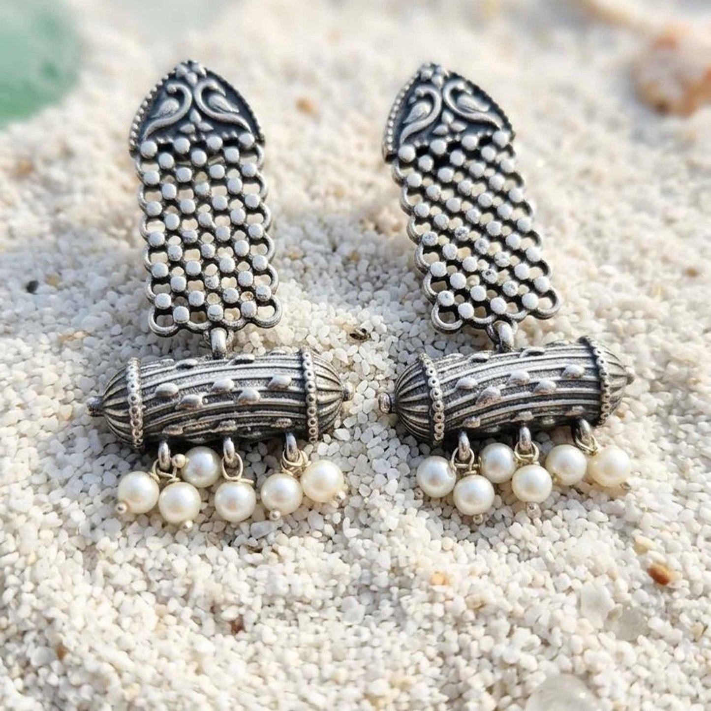 Heritage pearl dangler earrings displayed on white sand