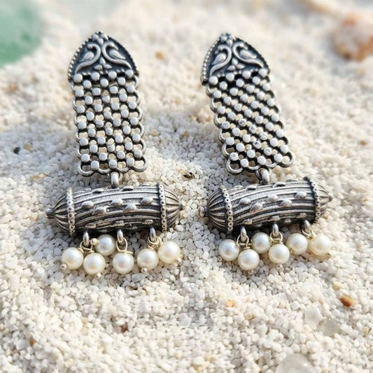 Heritage pearl dangler earrings displayed on white sand