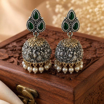 Traditional emerald jhumka earrings on wooden box