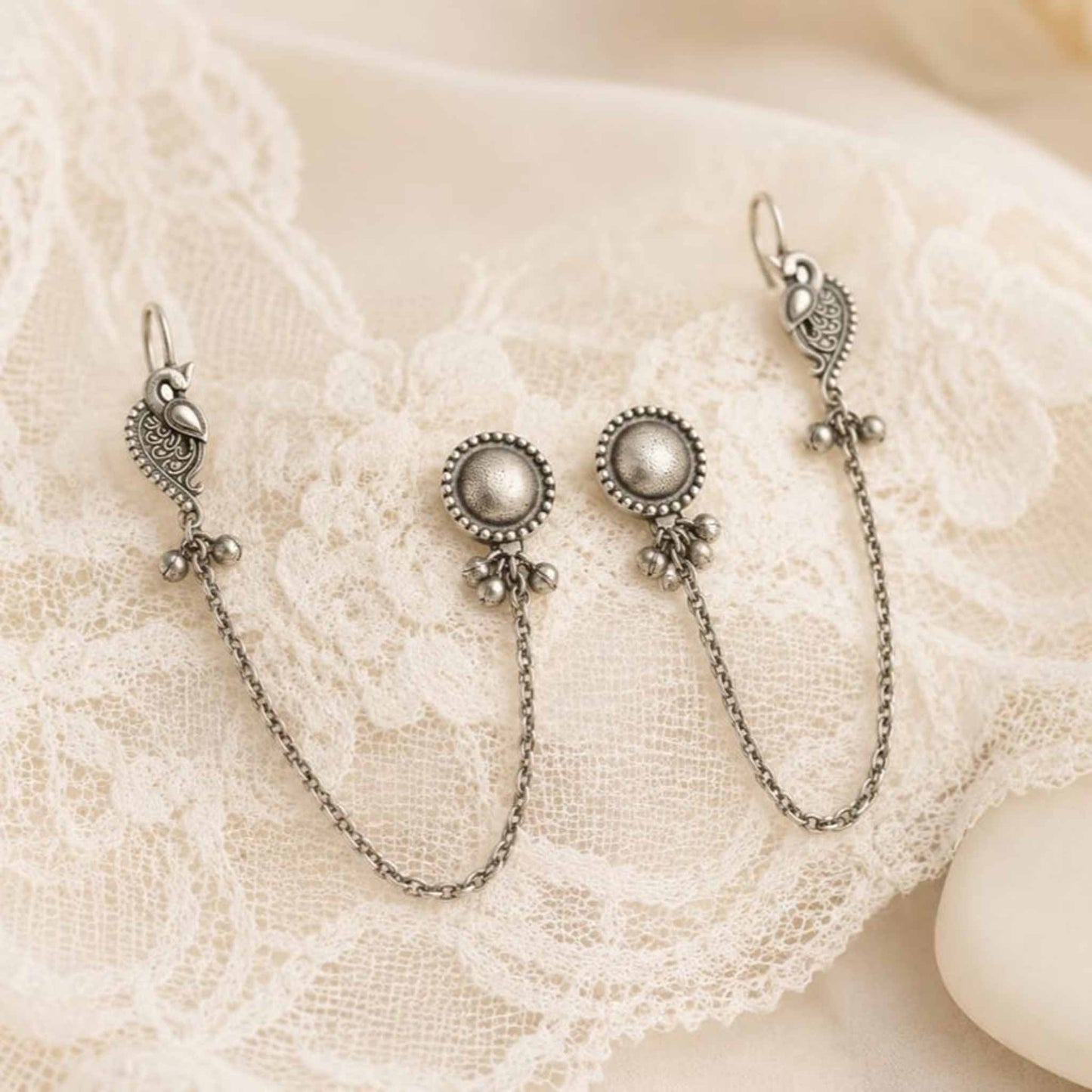 Peacock chain earrings displayed on white lace cloth
