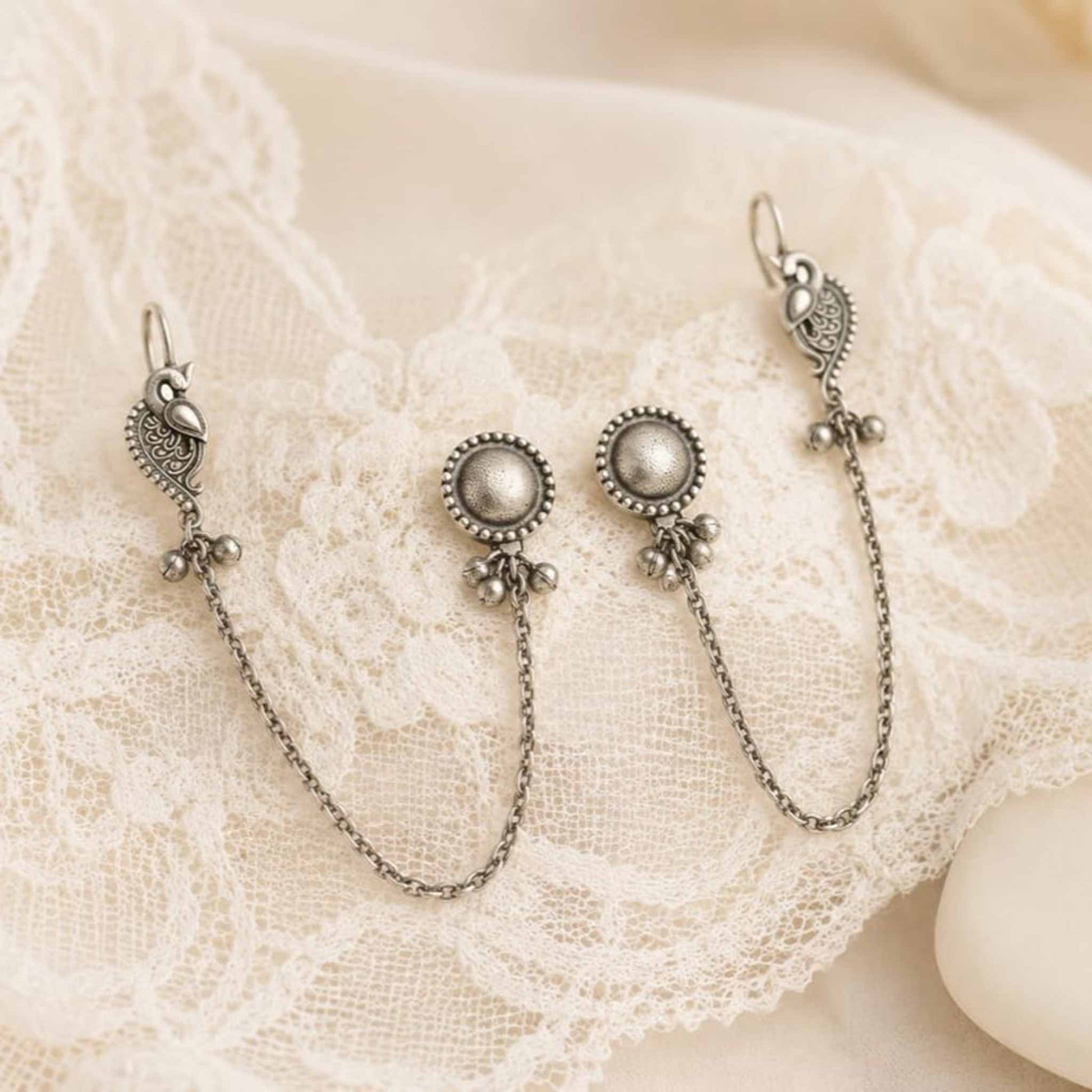Peacock chain earrings displayed on white lace cloth