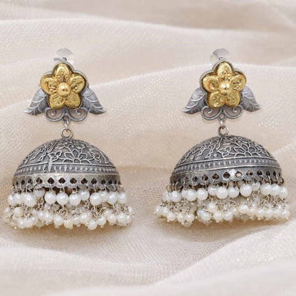 Closeup of floral pearl jhumka earrings on fabric backdrop