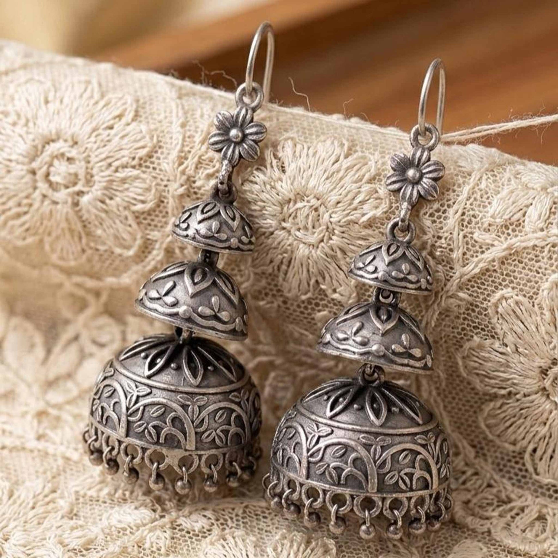 Detailed embroidered fabric flatlay of ethnic jhumka earrings