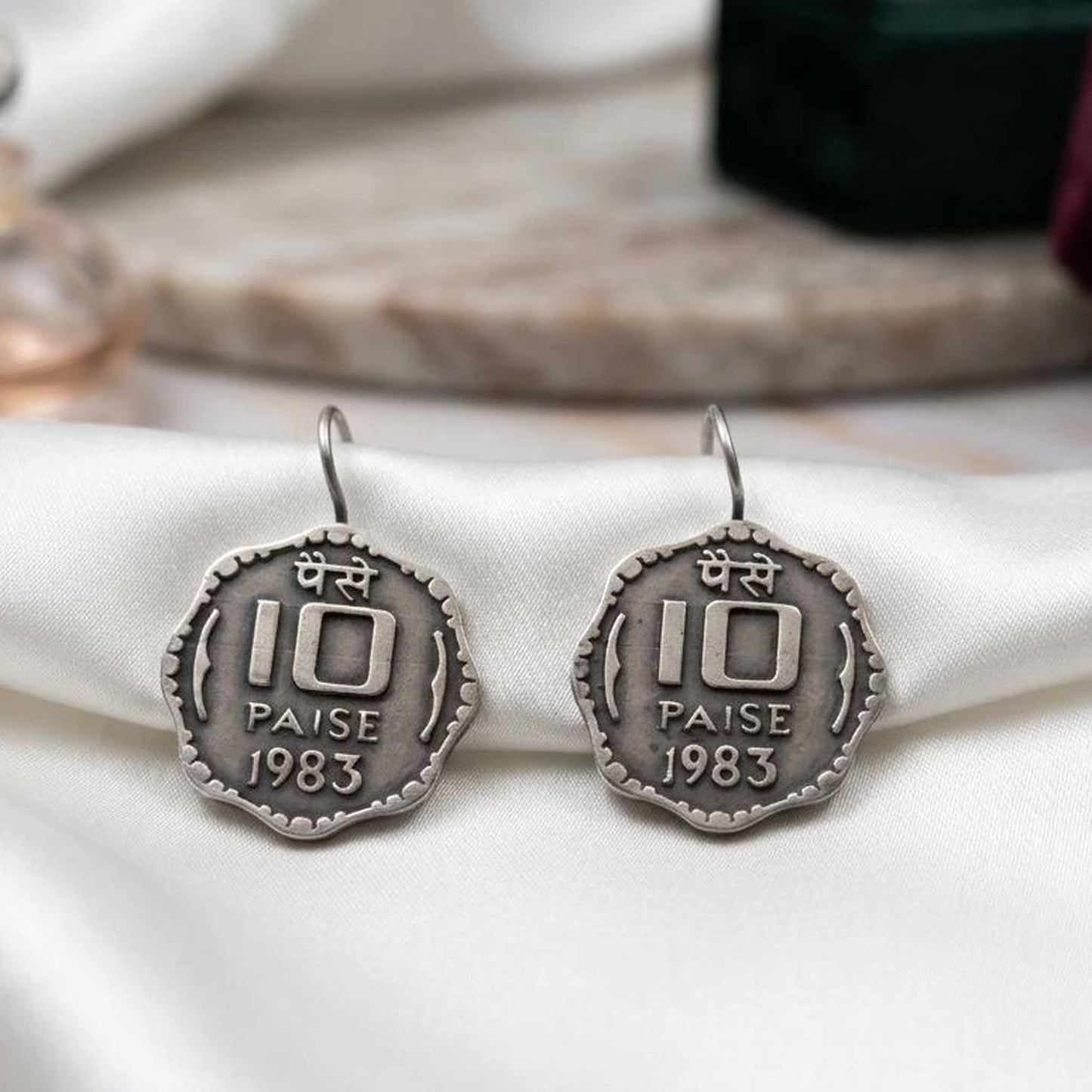 Vintage 1983 coin earrings displayed on fabric