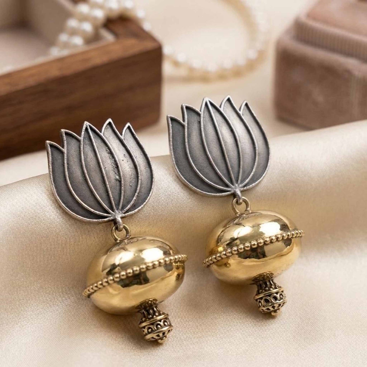 Lotus jhumka earrings styled on fabric background