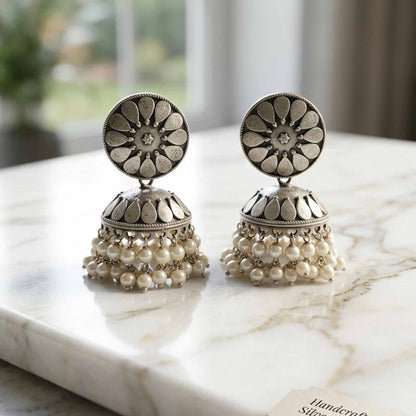 German silver pearl jhumka earrings on marble surface