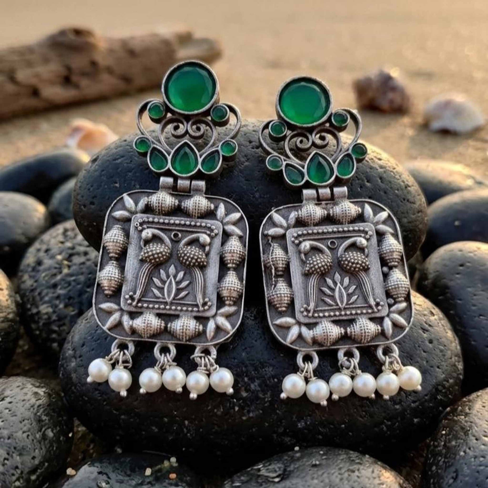 Emerald peacock German silver earrings displayed on black stones