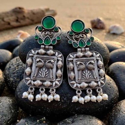 Emerald peacock German silver earrings displayed on black stones