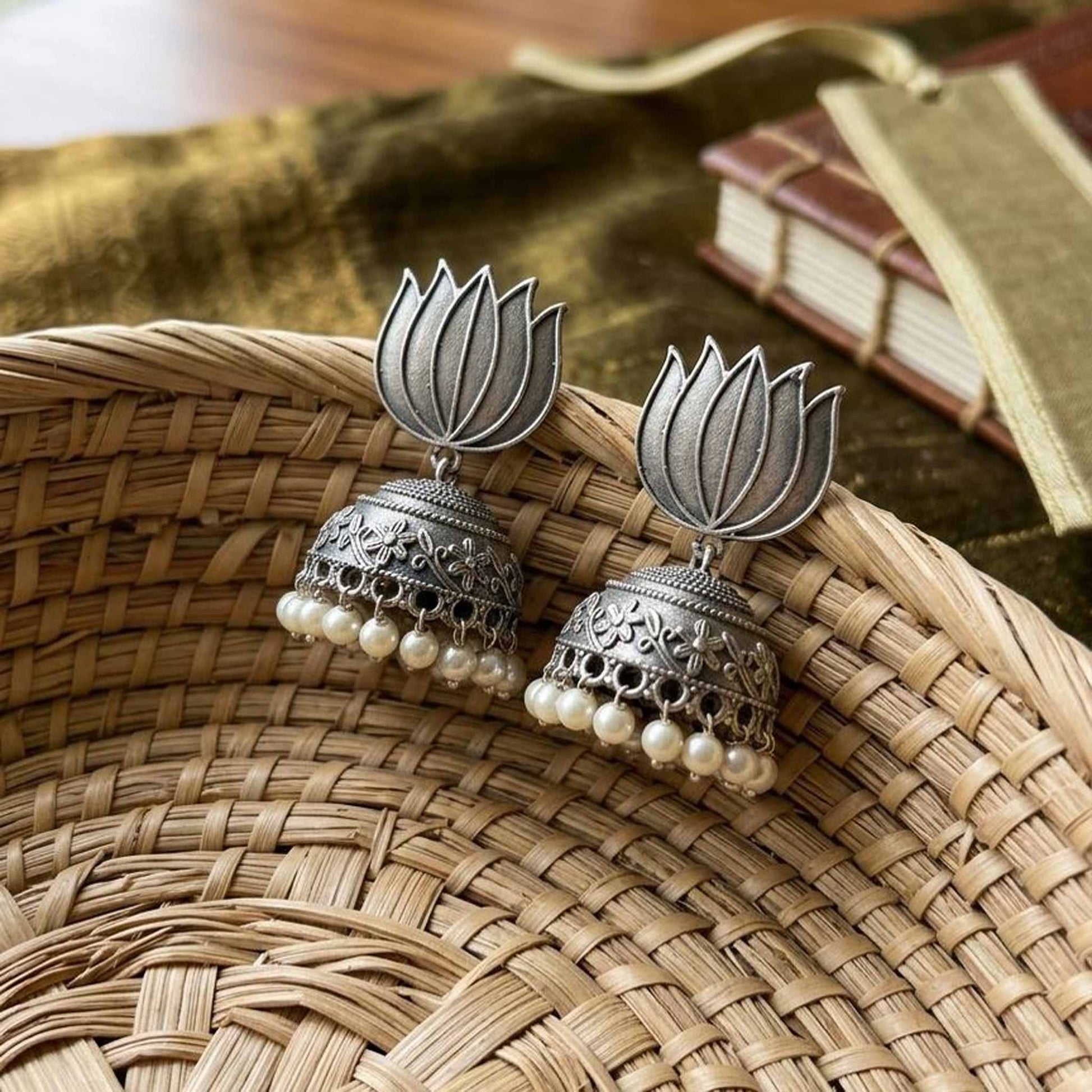 Lotus pearl jhumka earrings displayed in woven basket
