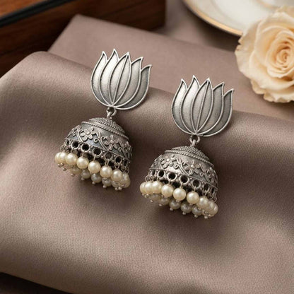 Close-up lotus pearl jhumka earrings on satin fabric
