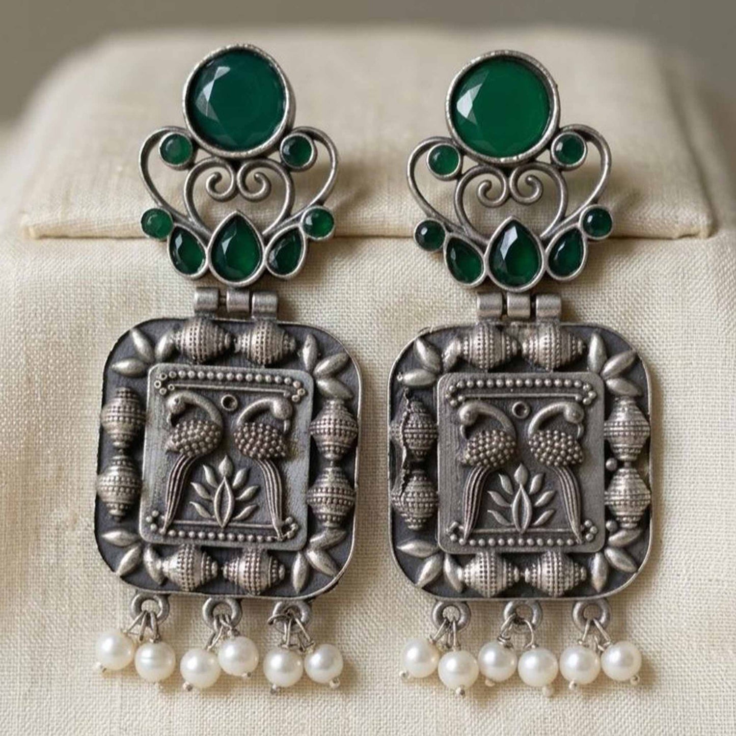 Closeup of embossed peacock German silver pearl earrings