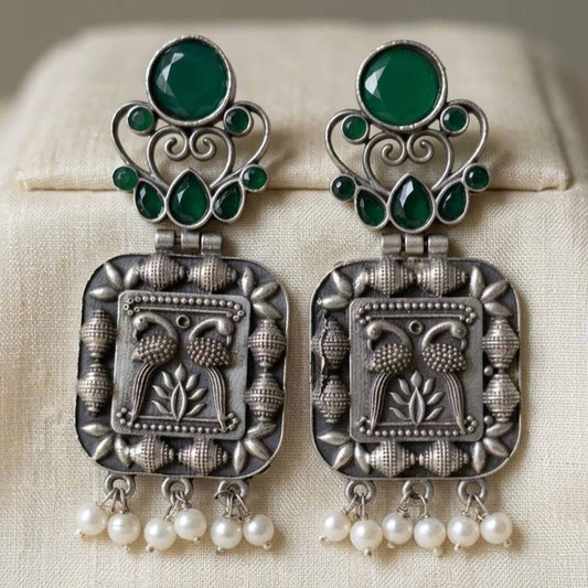 Closeup of embossed peacock German silver pearl earrings