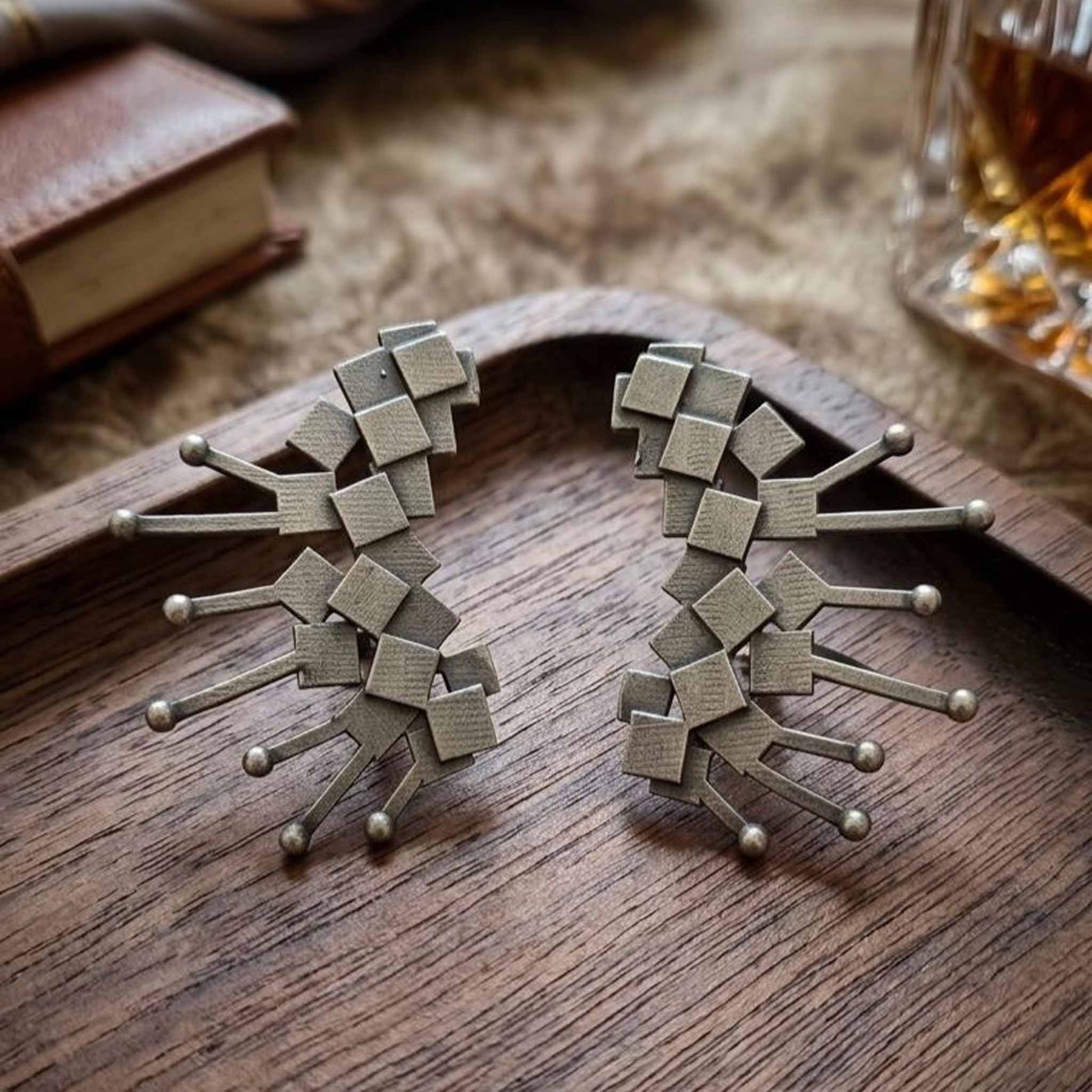 Geometric silver earrings on wooden tray