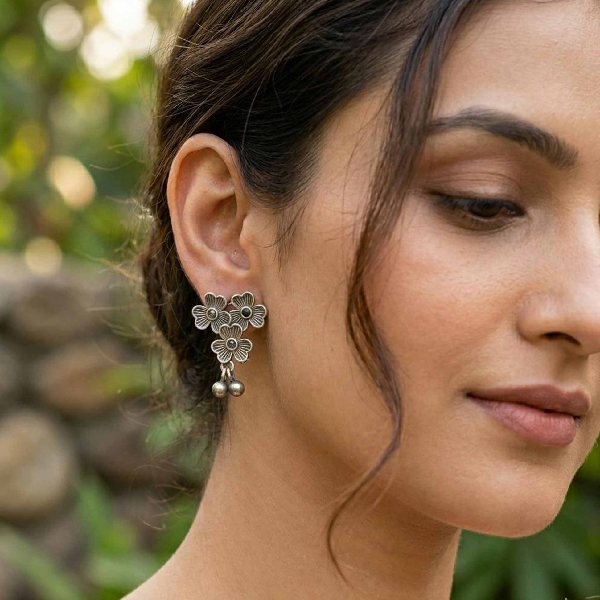 Woman wearing three flower German silver stud earrings