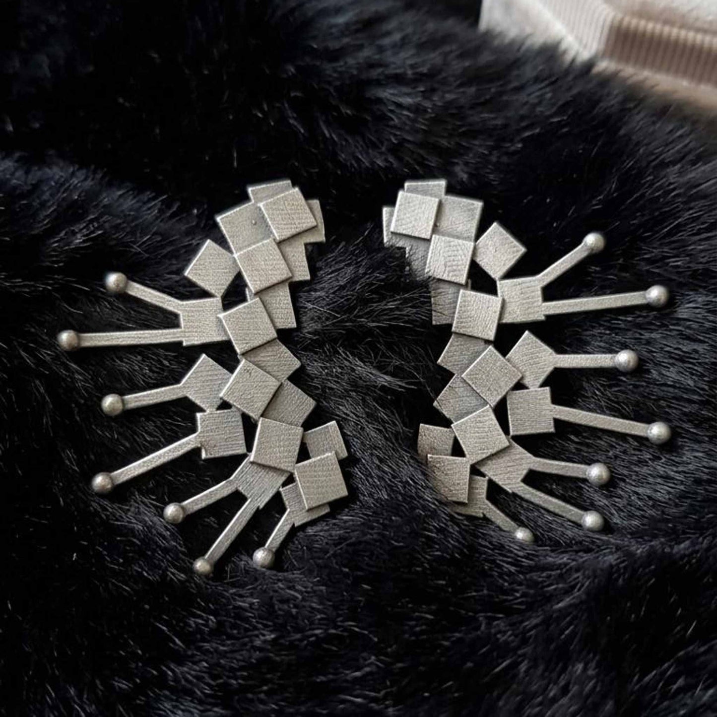 Abstract silver earrings on black backdrop