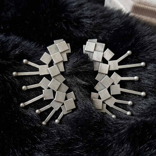 Abstract silver earrings on black backdrop