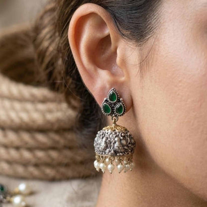 Model wearing emerald peacock embossed jhumka earrings