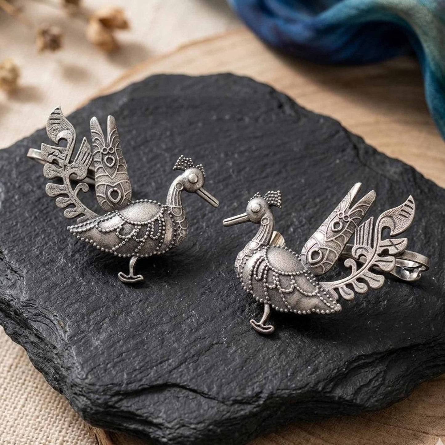 Peacock ear cuff earrings displayed on black stone