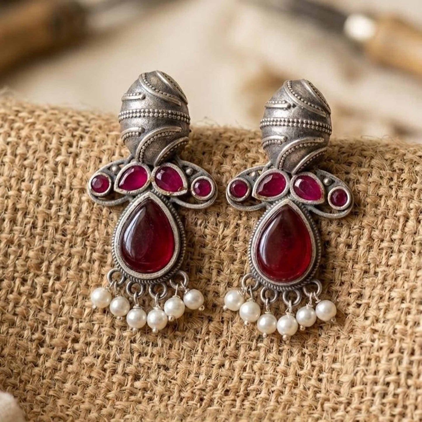 Ruby drop pearl earrings on textured fabric