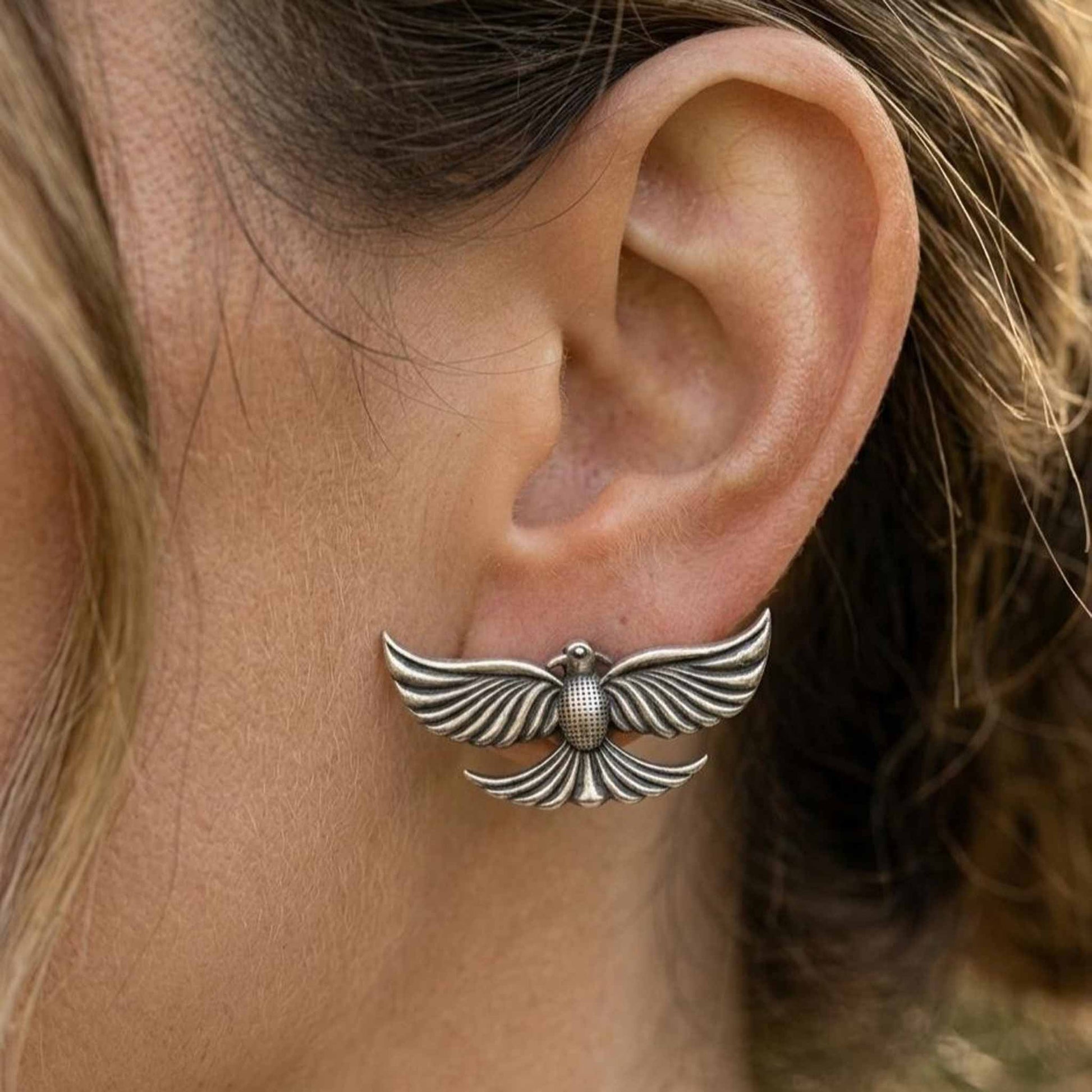 Closeup ear view of silver bird stud earrings