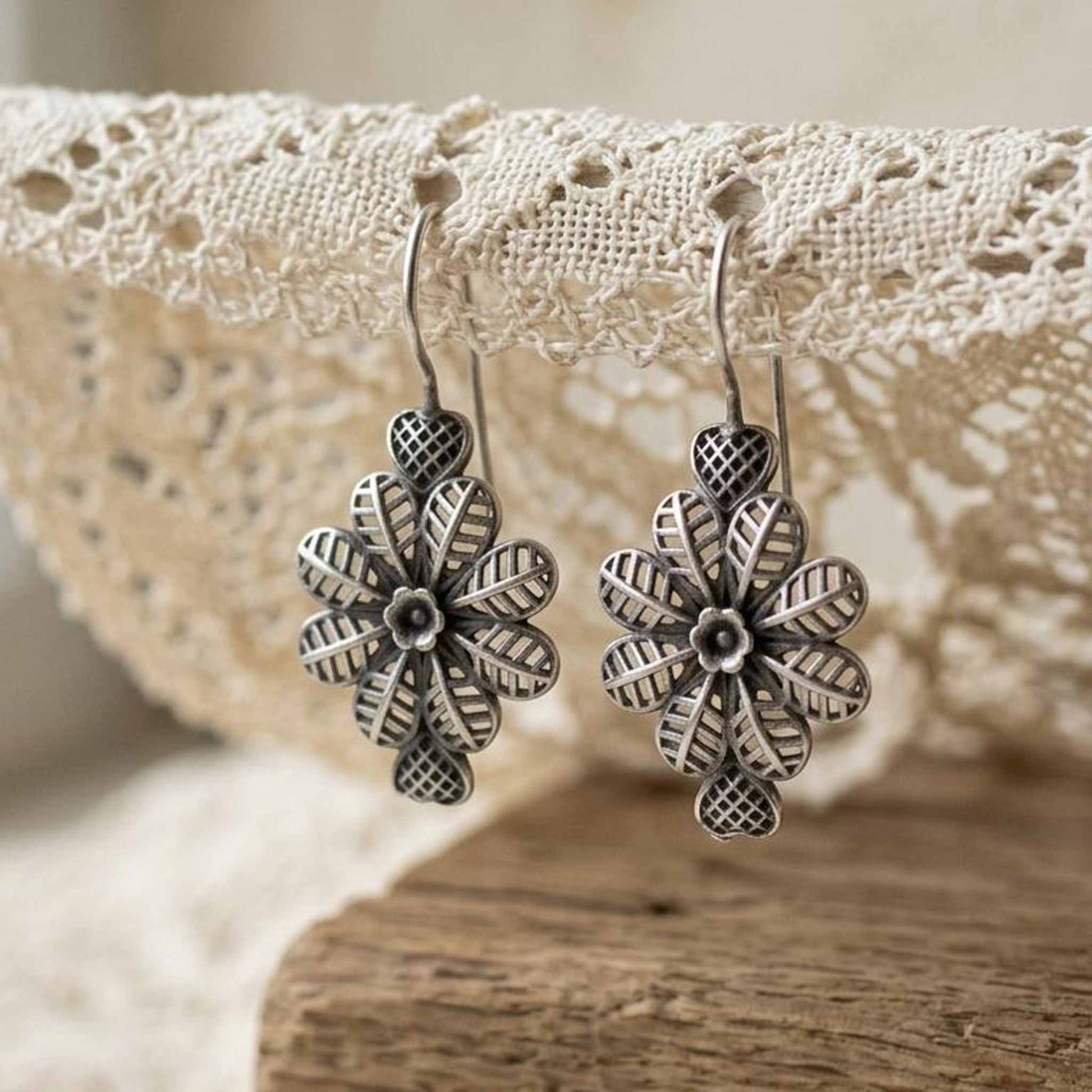 Floral heart earrings hanging on lace fabric