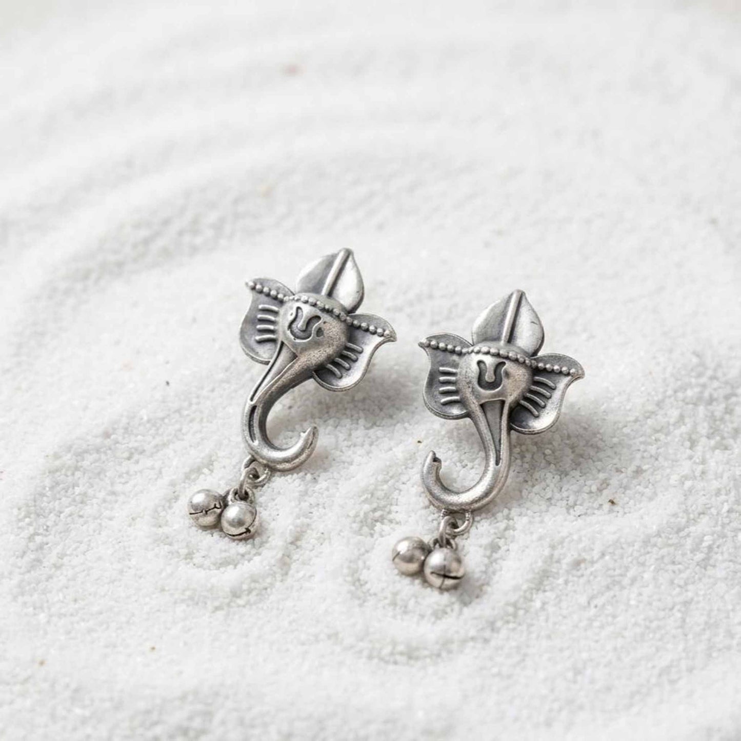 German silver Ganesha earrings closeup on white textured background