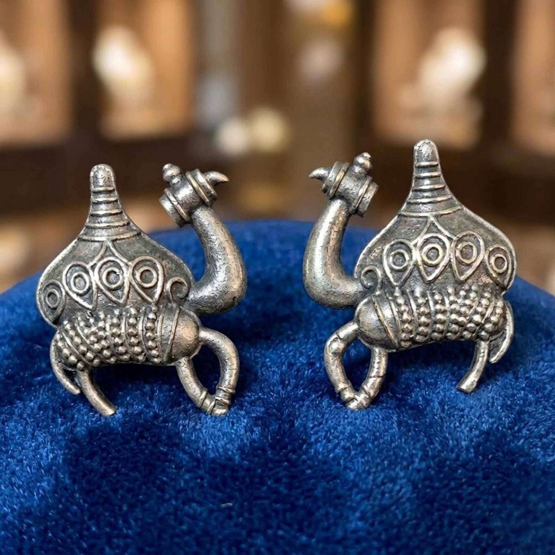 German silver camel stud earrings displayed on blue fabric