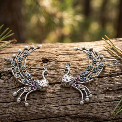 Traditional peacock ear cuff earrings on wooden texture