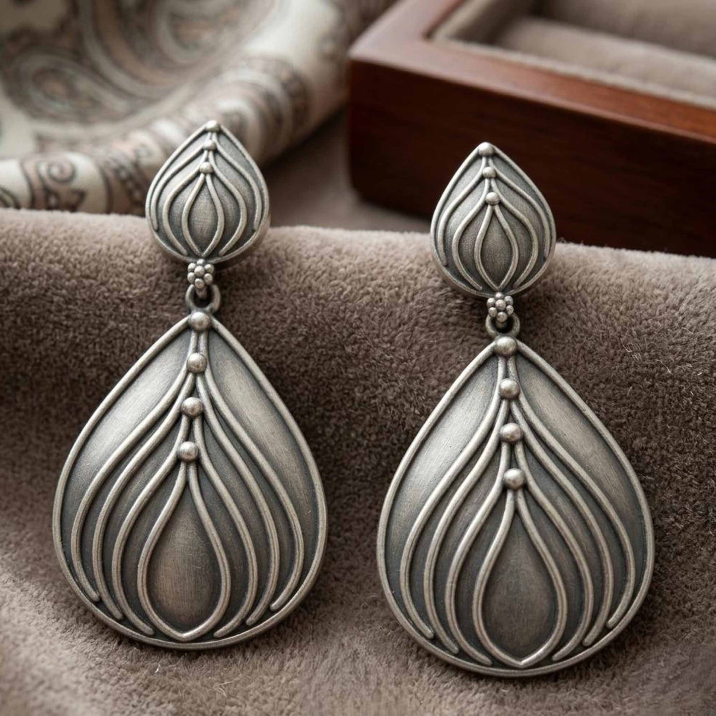 Closeup of lotus drop German silver earrings on velvet