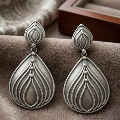 Closeup of lotus drop German silver earrings on velvet