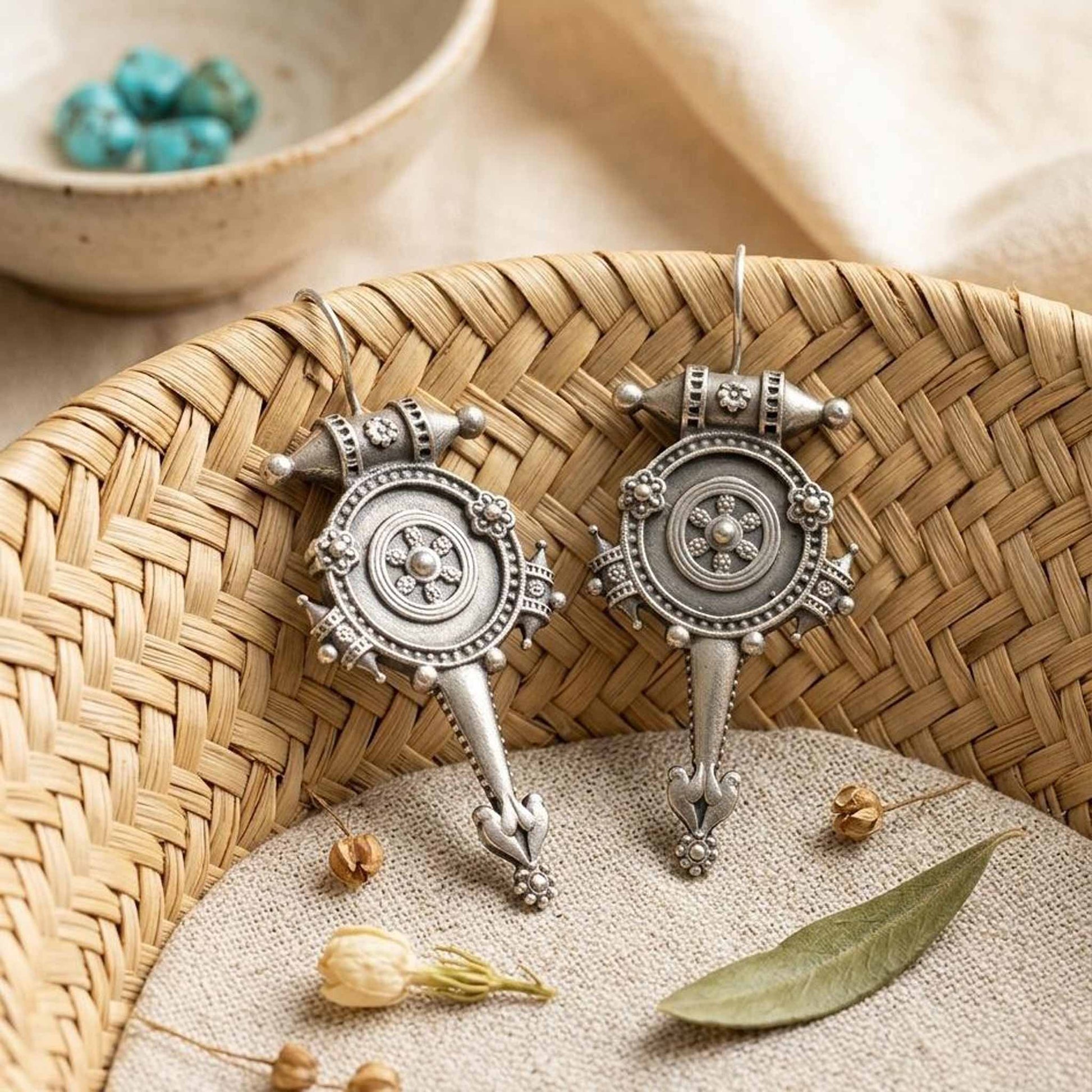 Traditional wheel motif hook earrings on woven tray