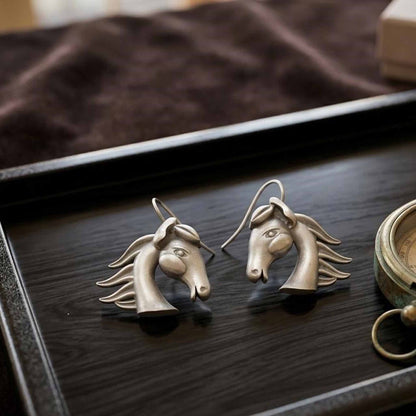 German silver horse earrings displayed on black tray