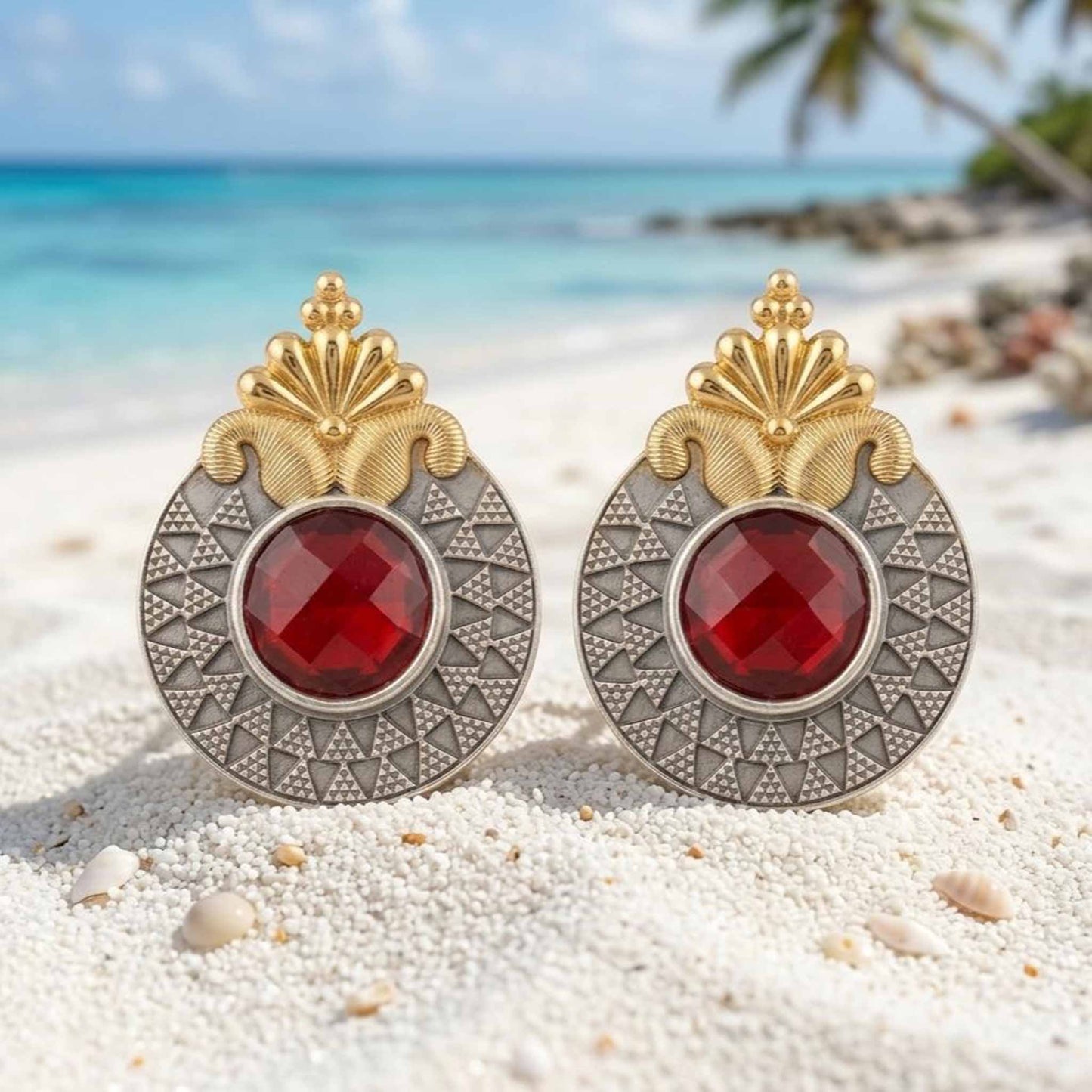 Ruby dual tone earrings displayed on beach sand