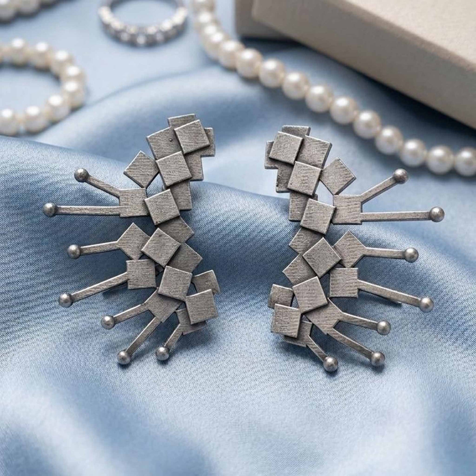 Contemporary silver earrings on satin backdrop