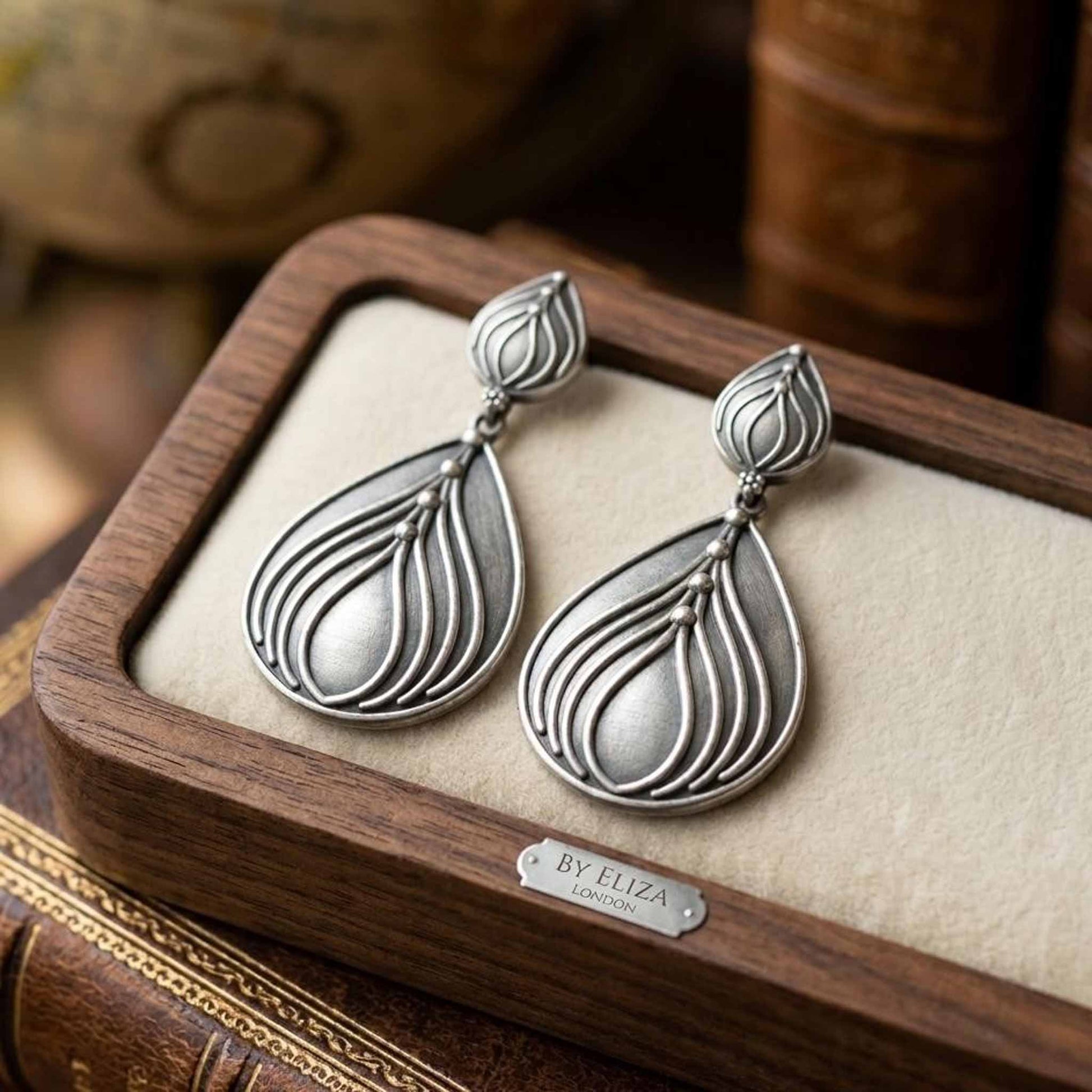 Lotus shaped German silver earrings displayed in wooden tray