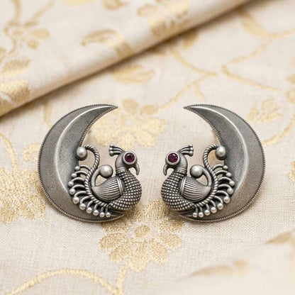 Peacock moon earrings placed on embroidered fabric backdrop