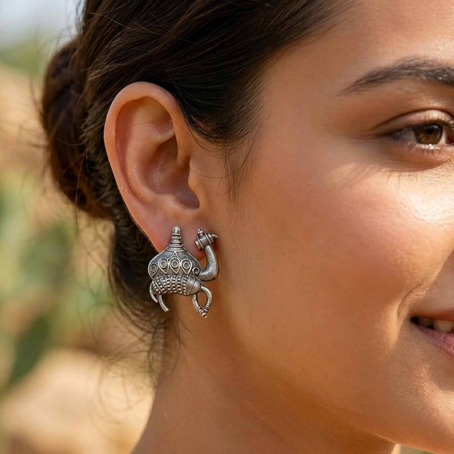Silver camel motif earrings worn on ear styling image