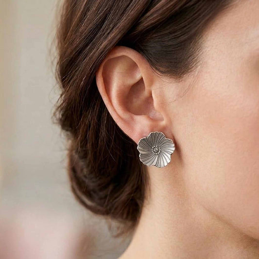 Silver floral stud earring worn by model